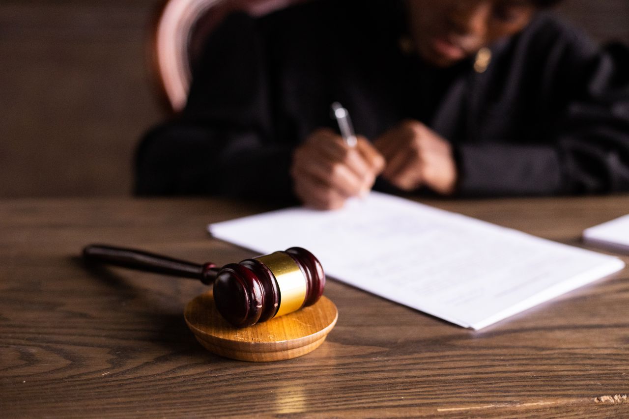 Home Judge signing documents at desk with focus on gavel, representing law and justice.