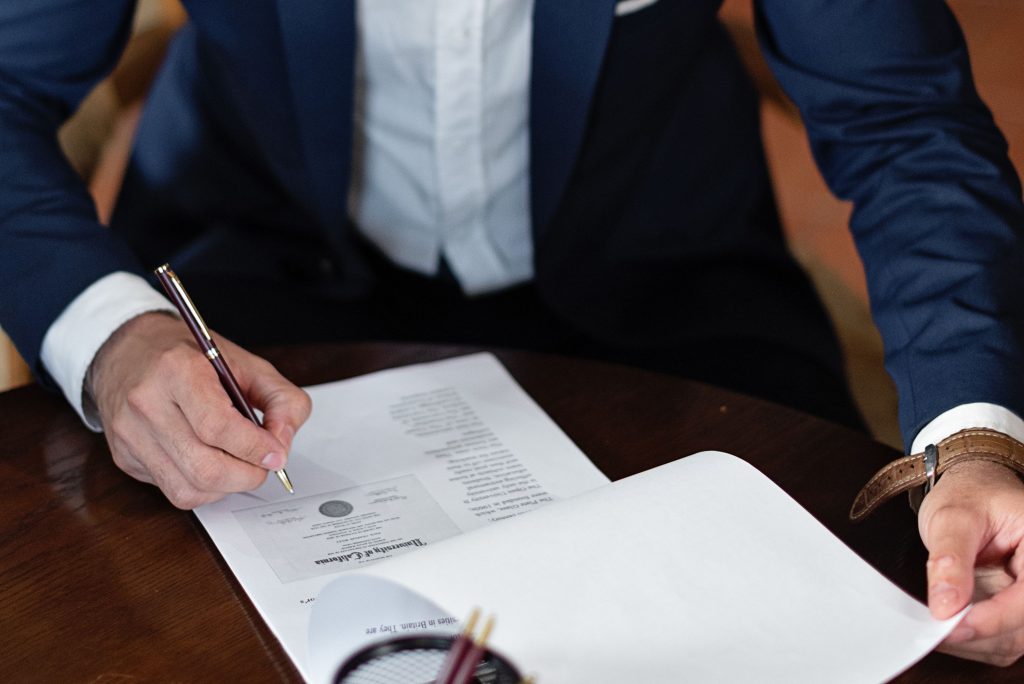 Preguntas Frecuentes A professional individual signs legal documents at a desk in an office setting.